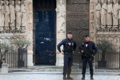 Dos policías vigilan junto a la catedral de Notre Dame en cuyo interior se puede ver una pila de escombros, este martes, en París (Francia). 