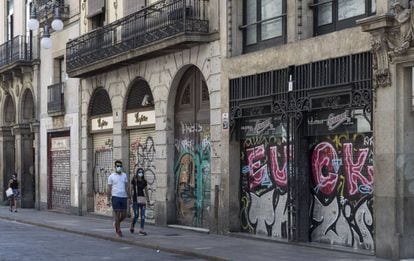 Una parella passejant pel carrer Ferran de Barcelona, amb la majoria d'establiments tancats.