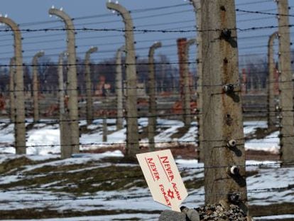 Una placa que dice &ldquo;Nunca de nuevo, nunca olvidar&rdquo; se levanta en unas piedras junto a la verja del campo de Auschwitz-Birkenau.