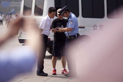 Agentes de policía comprueban las fotos tomadas por un hombre en la plaza de Tiananmen en Pekin. La vigilancia se ha incrementado con el fin de mantener el orden durante la jornada.