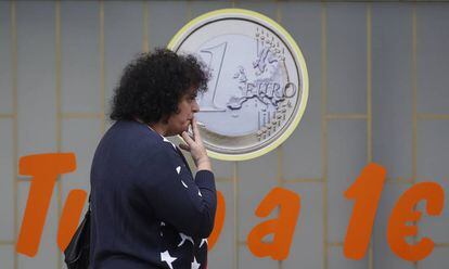 Una mujer fuma junto a un comercio de Lisboa.