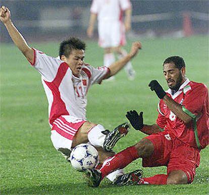 El chino Li Tie (a la izquierda) disputa el balón al omaní Al harbi en el partido de ayer en Shenyang.