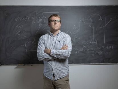 El matemático de Minesota, Jared Aurentz, en una sala del Instituto de Ciencias Matemáticas de Madrid. En la pizarra, partes de las fórmulas que representan la inteligencia artifical que aprende las reglas del dominó.