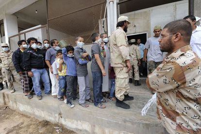 Hombres y ni&ntilde;os hacen cola en una sala de Misrata para ver los cad&aacute;veres de los Gadafi.