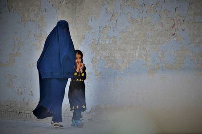 A burka-clad woman and a girl walk through Kabul in May 2022.