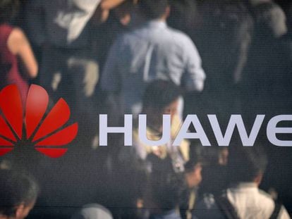 Varias personas se reflejan en un espejo con un logotipo de Huawei. 