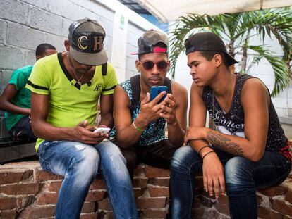 Tres jovenes conectados a Internet con sus móviles en el espacio de arte El Romerillo, en La Habana.