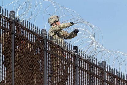 Soldados estadounidenses instalan alambrado en la valla fronteriza con México.