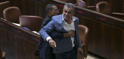 Un acomodador del parlamento israelí retira de la sala a un diputado árabe que protesta por la aprobación de la Ley del Estado Nación.