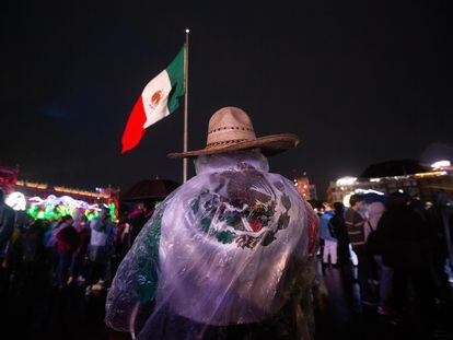 Un hombre se protege de la lluvia con una bandera en el Zócalo de Ciudad de México.