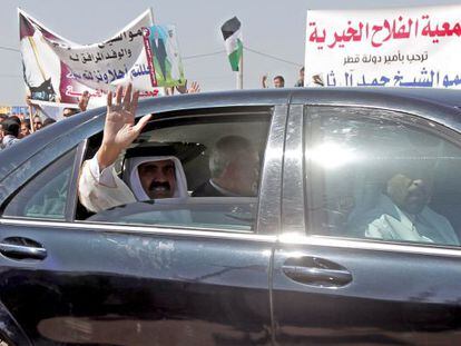 El emir de Catar saluda desde el coche junto al primer ministro palestino, Ismail Haniya, en Gaza.