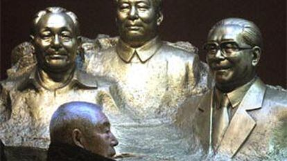 Un chino pasa junto a un grupo escultórico que representa a Deng Xiao Ping, Mao Zedong y Jian Zeming.