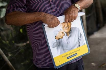 Un partidario enrolla un cartel con el candidato presidencial Rodolfo Hernández un día antes de la segunda vuelta presidencial del país, Bucaramanga, el 18 de junio de 2022.