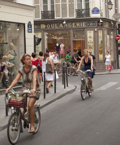 Dos ciclistas con bicis del sistema Vélib’, en la Rue des Francs Bourgeois de París.