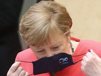 La acnciller alemana Angela Merkel se quita la mascarilla antes de un discurso en el Parlamento alemán. 