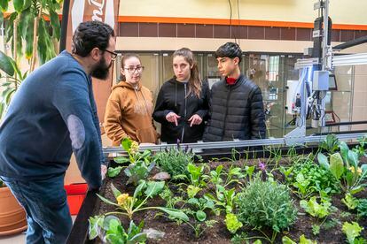 El profesor de botánica aplicada del IES Humanes de Madrid explica a los alumnos Elena Gómez, Nora Ferrero y Lorenzo Serrano el funcionamiento del robot agricultor instalado en el centro.