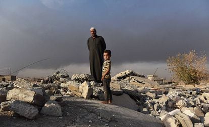 Salih Latif y uno de sus hijos, en la montaña de escombros que ha quedado de su hogar en Haji Alí.