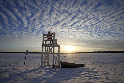 Una mujer observa la puesta de sol desde una silla de socorrista en el lago Calhoun absolutamente nevado, en Minneapolis.