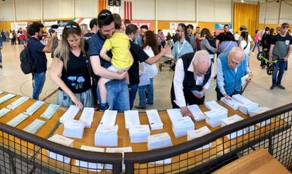 Varios votantes escogen sus papeletas durante las elecciones municipales, autonómicas y europeas en el colegio Pavello de Palau, Girona.