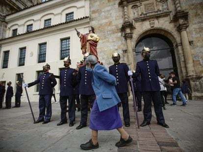 Una mujer camina junto a un grupo de penitentes que cargan una efigie de Cristo durante el pasado viernes santo, en Bogotá.