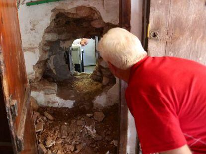 El director de la sucursal atracada en Nàquera mira por el agujero por el que entraron los butroneros.