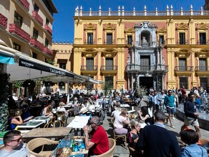 Numerosos clientes en terrazas de bares y restaurantes del centro histórico de Málaga, que conviven esta Semana Santa con las procesiones de las cofradías.