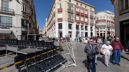 Varias personas caminan junto a las tribunas que se están montando para la próxima Semana Santa en Málaga, este jueves.