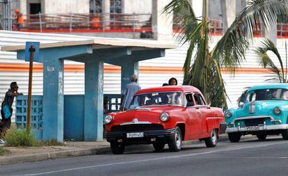 Dos automóviles clásicos pasan frente a una parada de autobus, el miércoles en La Habana (Cuba).