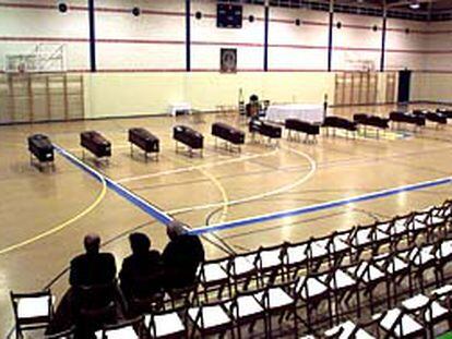 Tres familiares de algunas de las víctimas ante varios ataúdes en el Polideportivo de Palma del Condado.