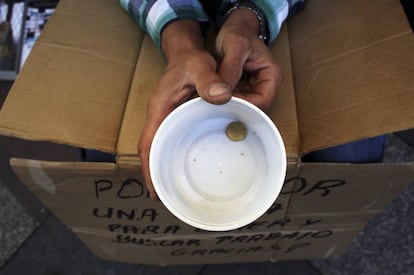 Un mendigo sujeta un vaso de plástico mientras pide dinero en Madrid.