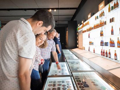 Visitantes del museo de Estrella Galicia contemplan etiquetas y botellas antiguas de la marca.