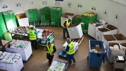 Varios voluntarios del Banco de Alimentos distribuyen las donaciones en un almacén.