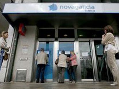 Varias personas esperan para sacar dinero de los cajeros de una sucursal de Novagalicia Banco. EFE/Archivo