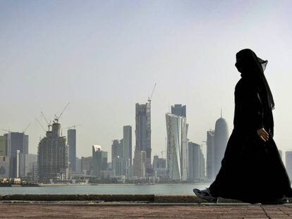 Una mujer camina frente a los rascacielos de Doha, Qatar. 