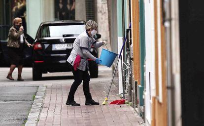Una mujer limpia la fachada de su vivienda en el centro de Córdoba.