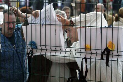 Varios votantes consultan sus nombres en el censo electoral a las puertas del colegio Madrid Sur con crespones negros, frente a la estación de cercanías de El Pozo del Tío Raimundo, lugar de uno de los atentados del 11-M.