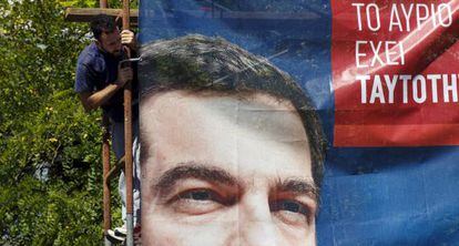 Un trabajador tras un cartel electoral de Syriza, hoy en Atenas