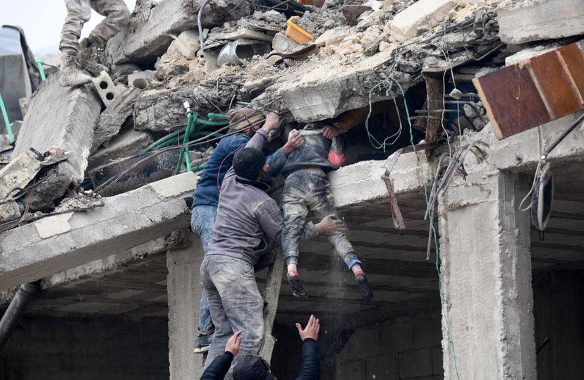 Varios residentes rescatan a una niña de un edificio colapsado en la ciudad siria de Jandaris.