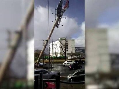 El viento derriba un anuncio sobre dos autos en México