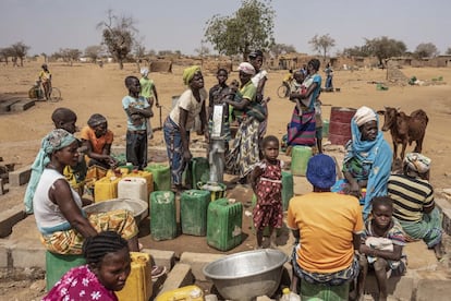 Mujeres y niños hacen fila para recoger agua en el campamento de desplazados internos de Barsalogho en Burkina Faso en marzo de 2020.