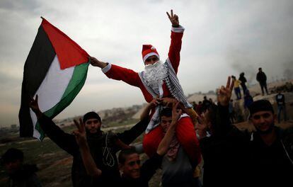 Un manifestante palestino, vestido con un traje de Santa Claus, porta una bandera de Palestina durante una protesta por la decisión de Trump de reconocer Jerusalén como la capital de Israel, al este de la ciudad de Gaza.