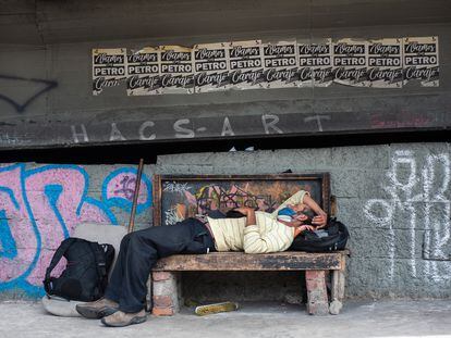 Un hombre duerme en un banco debajo de un puente, en Bogotá, el 3 de julio de 2020.
