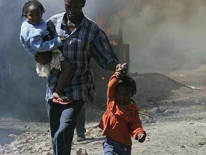 Un hombre y sus hijos entre los incendios en un suburbio de Nairobi.