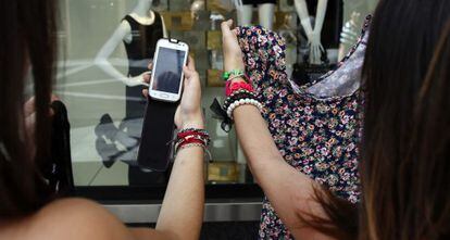 Dos mujeres buscan en internet el artículo que encuentran en un comercio.