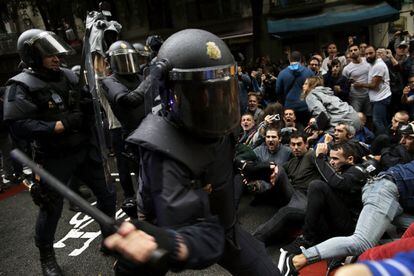 La Policia Nacional intenta desallotjar els votants del referèndum que s'asseuen en un carrer de Barcelona.