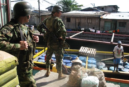 Integrantes de las fuerzas especiales del Ejército colombiano vigilan un bote que carga barriles para ser usados en laboratorios de cocaína.