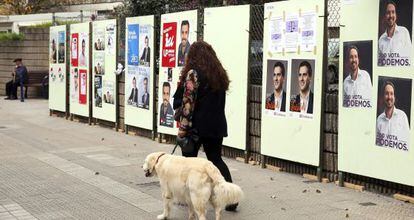 Una mujer pasa por delante de carteles electorales de distintos candidatos.