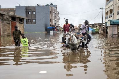 Varias personas avanzan por una calle inundada en Keur Massar (Dakar).
