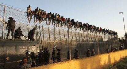 Decenas de inmigrantes encaramados a la valla de Melilla.