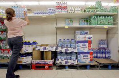 Una trabajadora repone botellas de agua en los estantes de un supermercado. EFE/Archivo